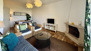 A living room with a sofa, chairs, a coffee table, a fireplace, and a television. - Praia DA Rocha Twins 5 by Homing (Portimão)