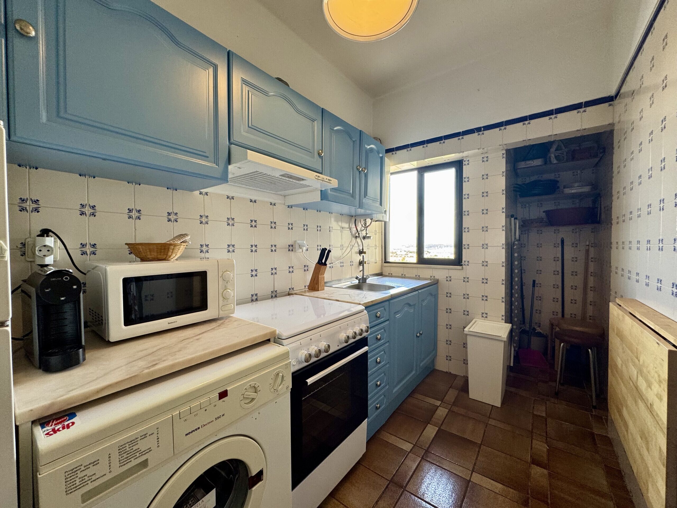 A kitchen with blue cabinets, a microwave, a stove, and a washing machine.