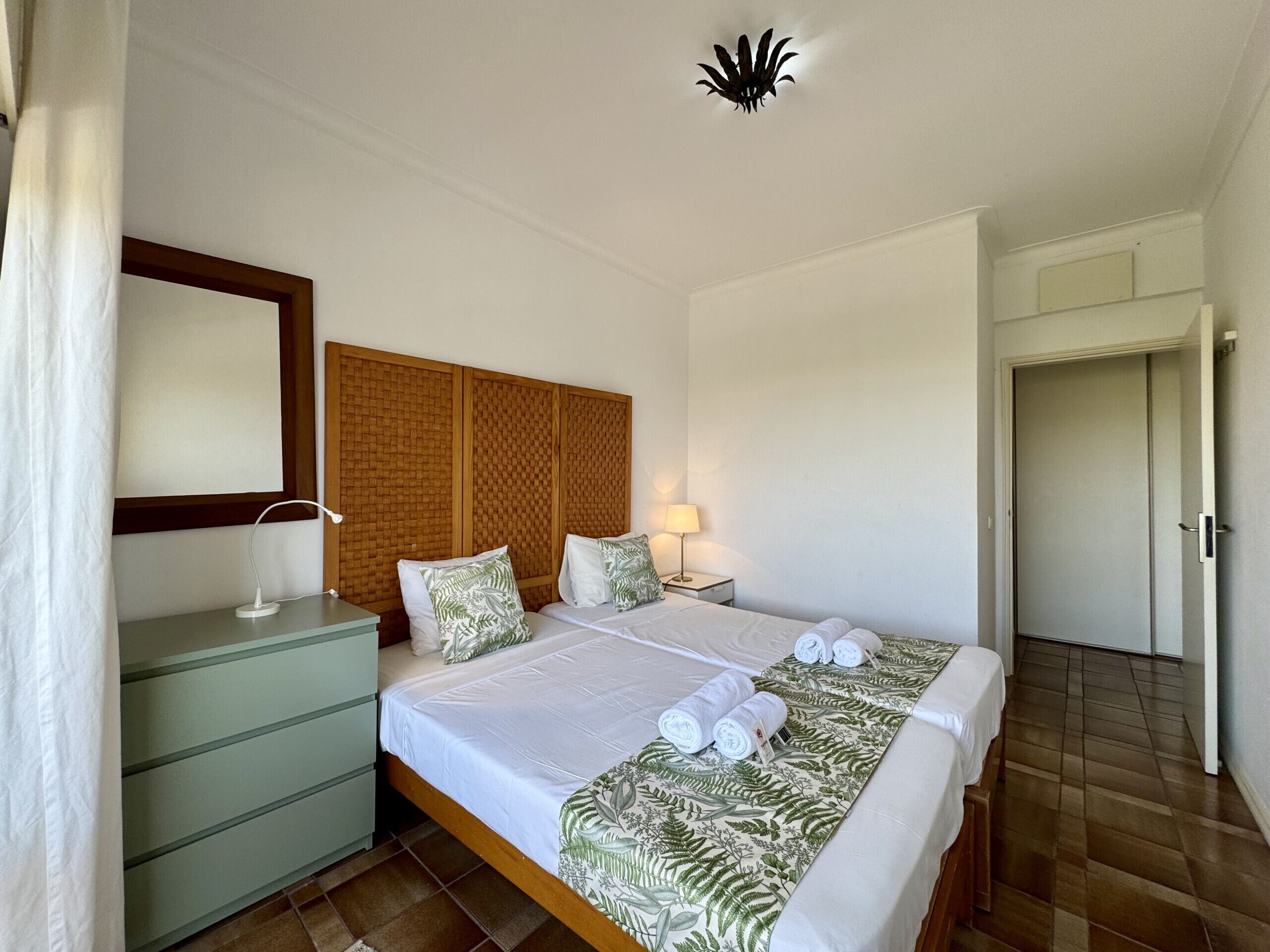 A hotel room with a large bed, a bedside table, a lamp, and a mirror.