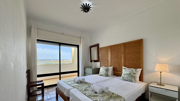Camera d'hotel con un letto grande, un comodino, una lampada, vista sul mare e una luce a soffitto.