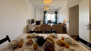 Angolo ristoro con tavolo apparecchiato per la colazione, camino e vista sul soggiorno.