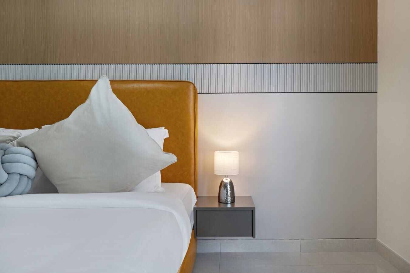 Une chambre d’hôtel avec un lit, une table de chevet et une lampe.
