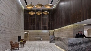 A modern hotel lobby with a reception desk, seating area, and decorative lighting. - Luxury Holiday Home | Spacious & Fully Furnished (Dubai)