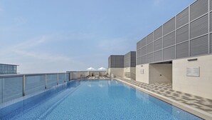 A rooftop swimming pool with a clear view of the sky, a glass balustrade, and a modern building facade. - Luxury Holiday Home | Spacious & Fully Furnished (Dubai)