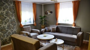 A living room with a sofa, two armchairs, a coffee table, and a potted plant. - Ferienwohnung Klüger - Vacation for the small family (Liebstadt)