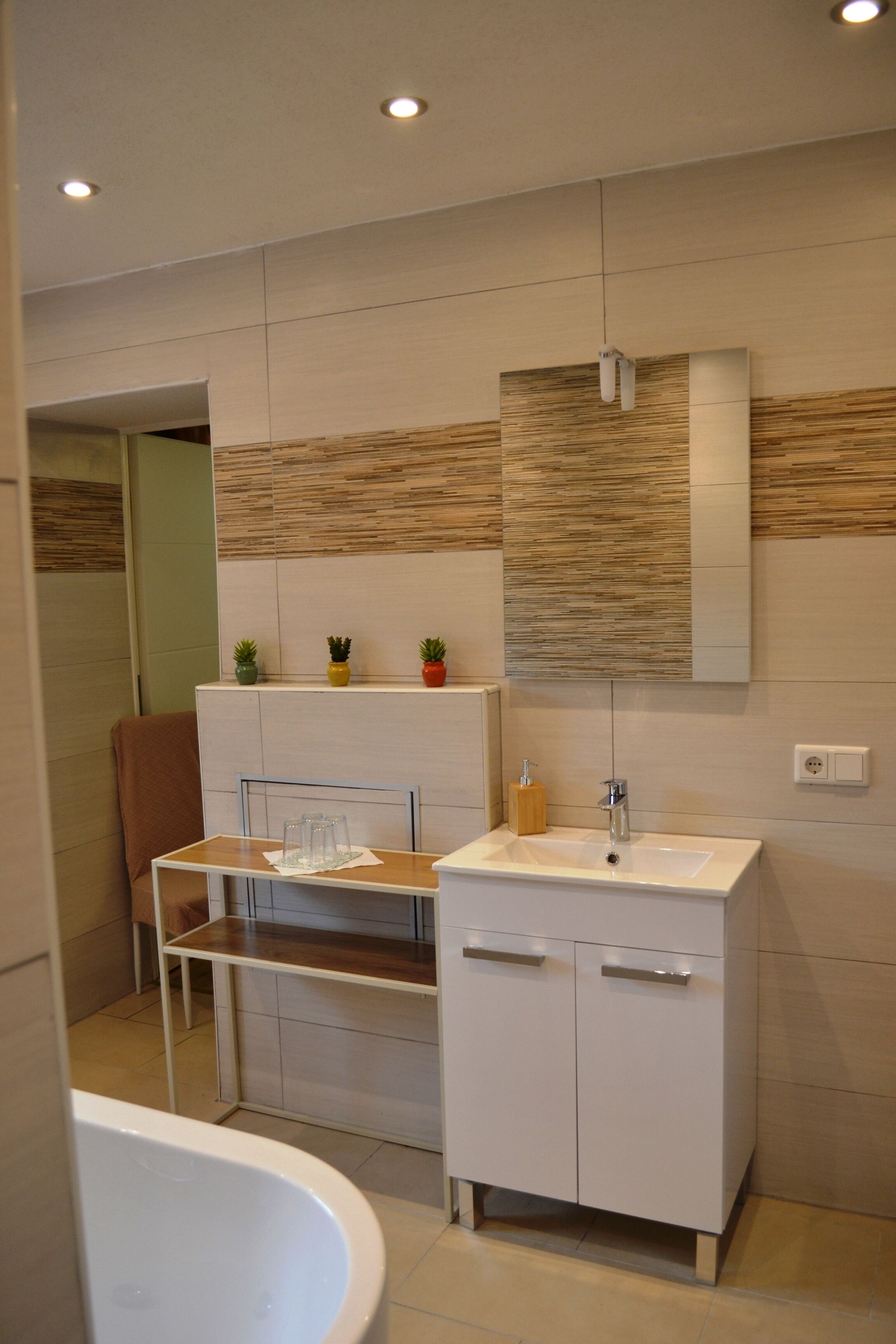 A modern bathroom with a white sink, mirror, and a bathtub.