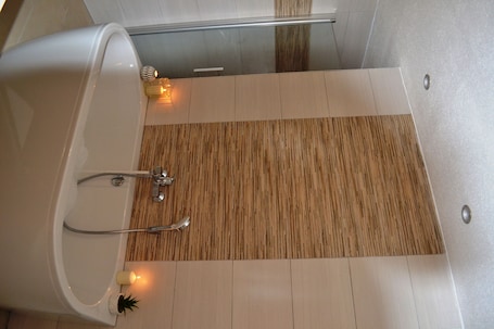 A modern bathroom with a bathtub, wooden floor, and a small plant.. Ferienwohnung Klüger - Vacation for the small family