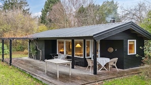 Eine kleine Holzhütte mit einer Veranda, einem Tisch und Stühlen.