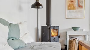 Ein Zimmer mit einem Bett, einer schwarzen Lampe, einem Kamin, einem gerahmten Bild und einem kleinen Tisch mit einer Schale.