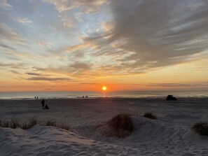 Ein Strand mit Dünen und einem Sonnenuntergang.