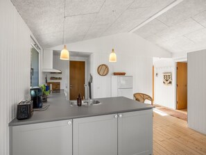 Eine moderne Küche mit Kochinsel, Pendelleuchten und Blick in den Essbereich.