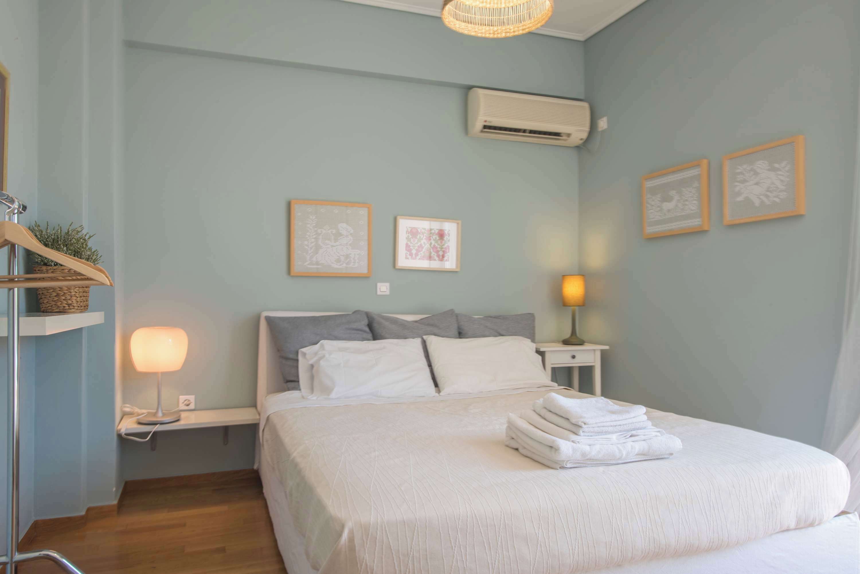 Un lit bien fait, avec des oreillers, une lampe de chevet et une serviette pliée posée sur le lit.