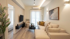 Una sala de estar moderna con un sofá, una mesa de centro, televisor y una obra de arte en la pared.
