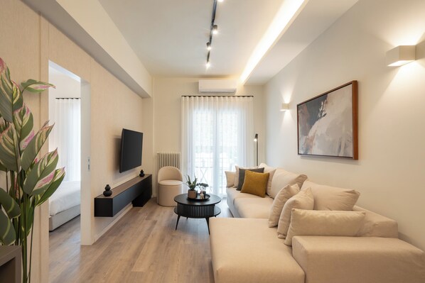 Una sala de estar moderna con un sofá, una mesa de centro, televisor y una obra de arte en la pared.