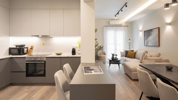 Una cocina moderna con electrodomésticos integrados, un comedor con mesa y sillas, y una sala de estar con sofá y mesa de centro.