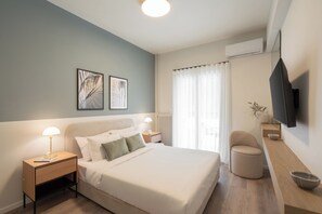 Un dormitorio moderno con cama, mesitas de noche, televisor y ventana con cortinas.