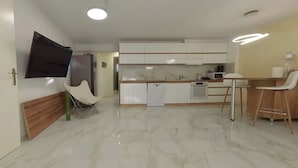 A modern kitchen with white cabinets, a marble countertop, and a flat-screen TV mounted on the wall. - Charming 3-bedroom House Rental in Málaga, Spain (Málaga)