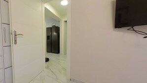 A hallway with a white wardrobe, a television mounted on the wall, and a refrigerator in the background. - Charming 3-bedroom House Rental in Málaga, Spain (Málaga)
