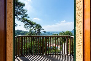 A balcony with a view of a mountainous landscape and a distant building. - Villa la Leccia by MMega (Massarosa)