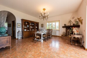 Een eetgedeelte met een houten tafel en stoelen, een kroonluchter en een decor kast.