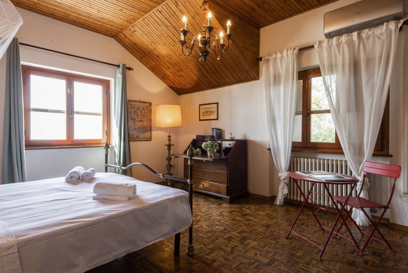 Ein Zimmer mit einem Bett, einem Schreibtisch, einem Stuhl, einem Heizkörper und einem Vorhangfenster.