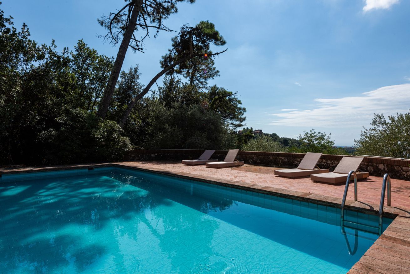 A swimming pool with lounge chairs and a stone wall.