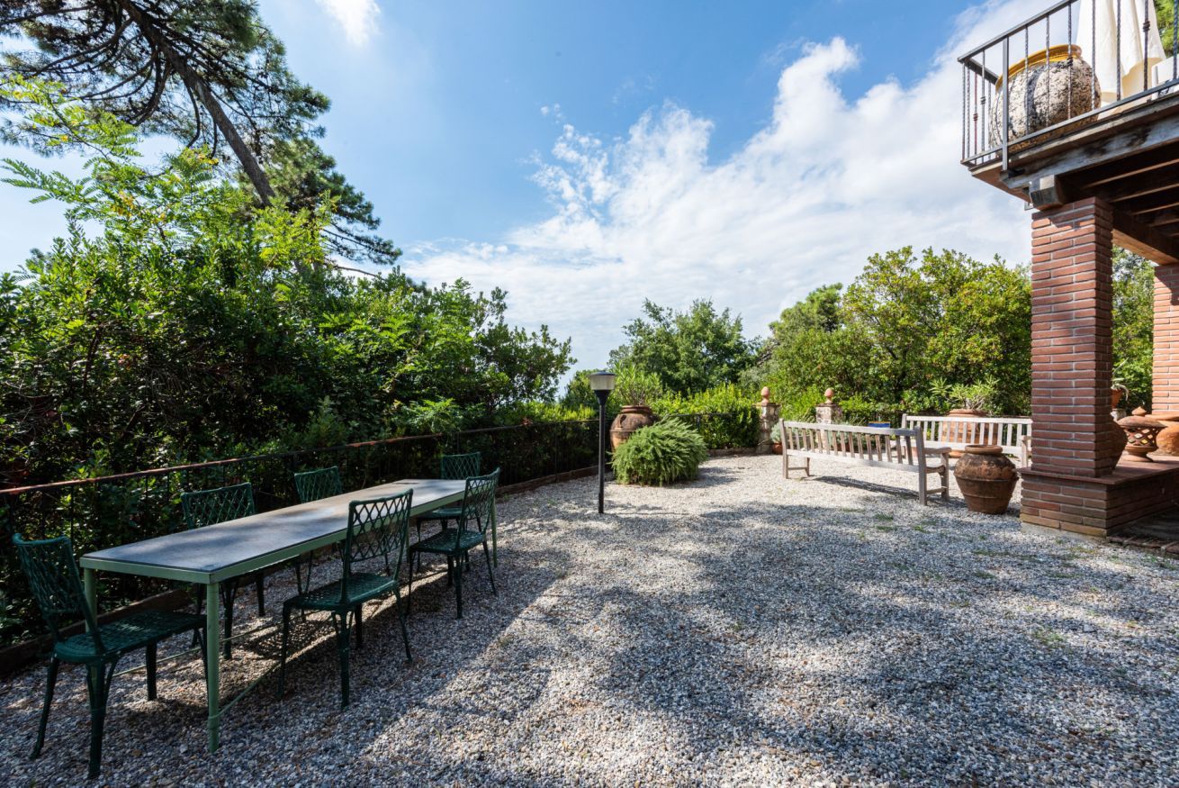 An outdoor patio with a table and chairs, surrounded by gravel and greenery.