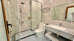 A modern bathroom with a glass-enclosed shower, a toilet, a sink, and a hairdryer. - O Lily Hotel (Ninh Binh)