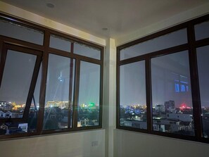 A room with large windows, a visible cityscape, and a ceiling with recessed lighting. - O Lily Hotel (Ninh Binh)