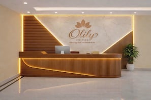 A hotel reception desk with a modern design, a marble wall, and a logo. - O Lily Hotel (Hoa Lu)