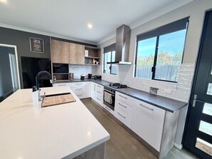 A modern kitchen with white cabinetry, a large island, a gas stove, and a window providing a view of the outdoors.