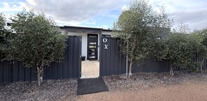 Un edificio moderno con una reja de metal negro, una puerta con ventanal y un letrero con las letras 'OX'.