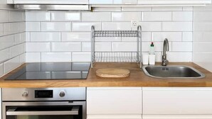 Eine Küche mit weißen Schränken, einem Edelstahlbackofen, einer Spüle und einer Holz Arbeitsplatte.