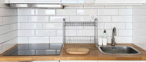 Een keuken met witte kasten, een roestvrijstalen oven, een spoelbak en een houten aanrecht.