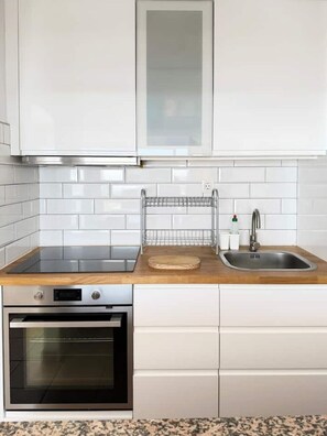 A kitchen with white cabinets, a stainless steel oven, a sink, and a wooden countertop. - Roca Negra (Tías)