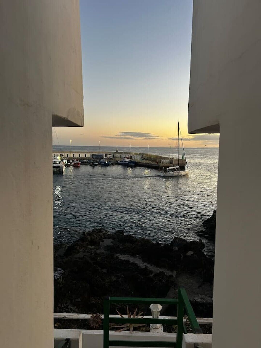 En vy över en hamn med båtar och en brygga, sedd genom ett fönster i en byggnad.