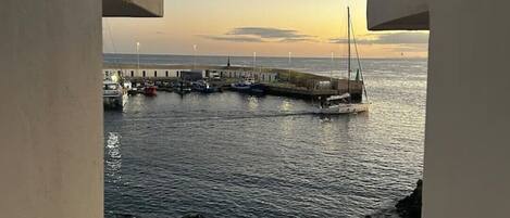 En vy över en hamn med båtar och en brygga, sedd genom ett fönster i en byggnad.