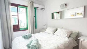 Ein Schlafzimmer mit Bett, Nachttisch, Spiegel und Klimaanlage.