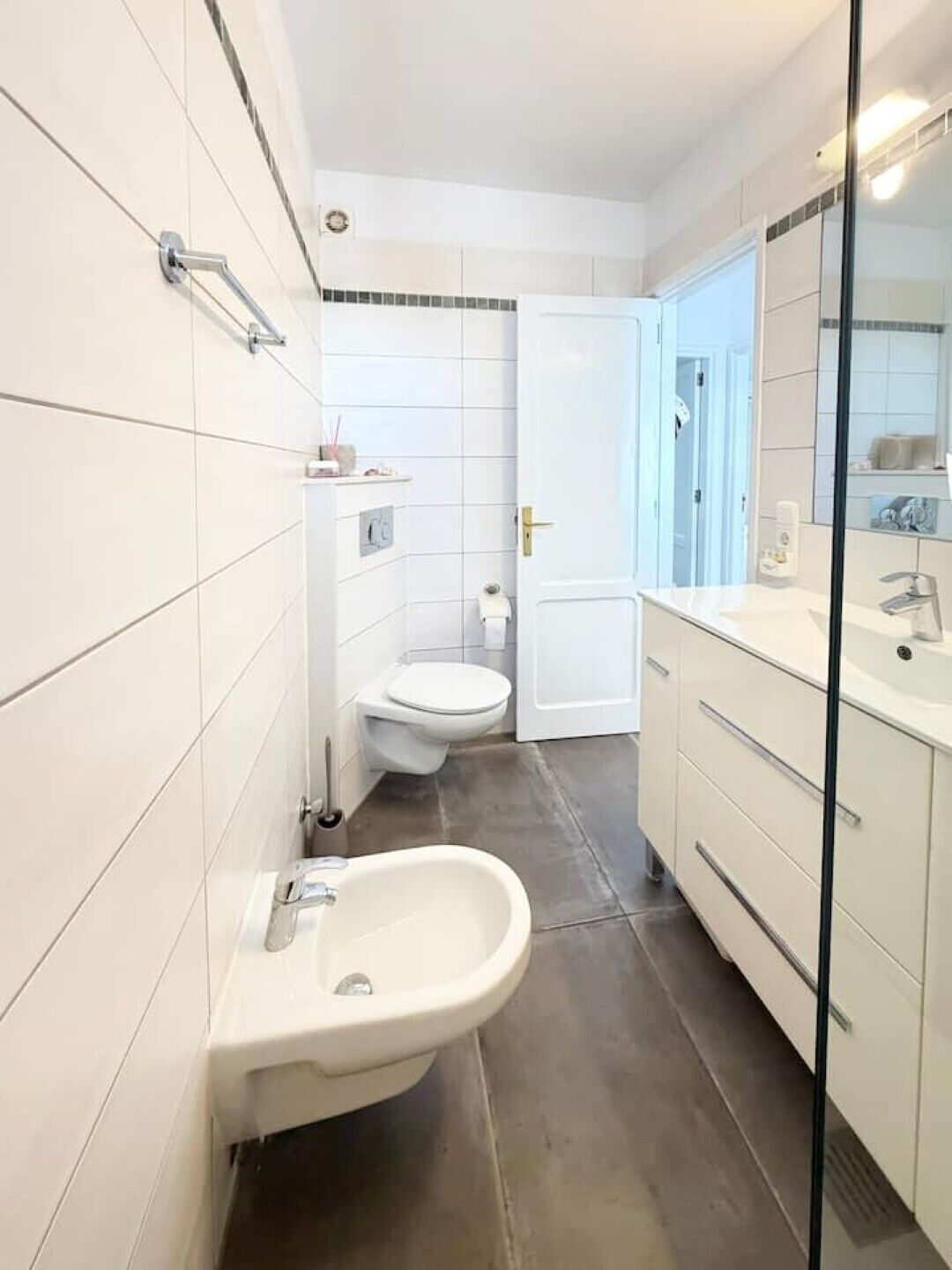 A bathroom with a bidet, toilet, and a sink with a mirror.