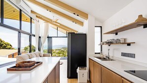 Eine moderne Küche mit einer großen Kochinsel, Holzschränken und Blick ins Freie.
