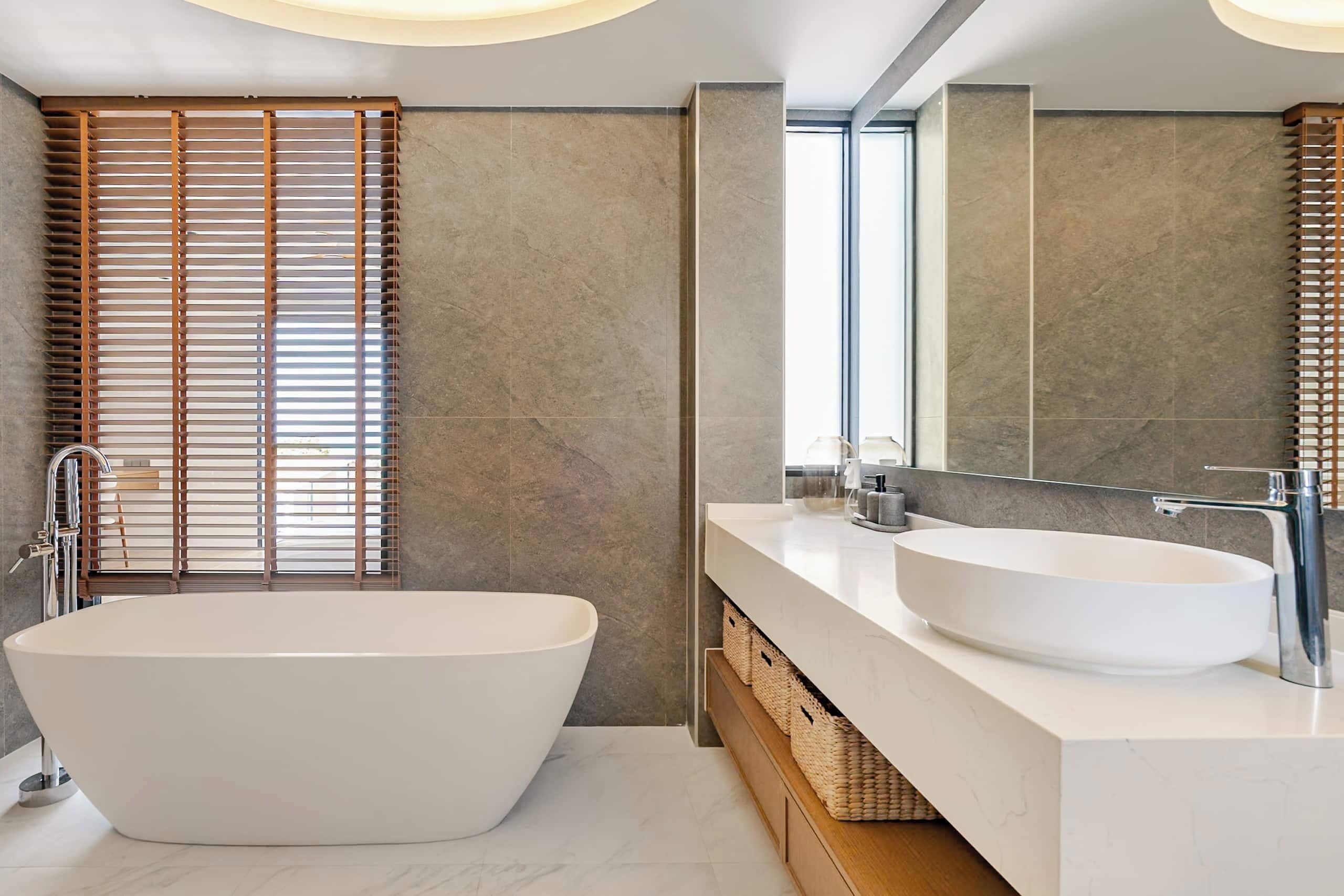 A modern bathroom with a freestanding bathtub, two sinks, and a large mirror.