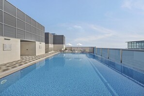 Ein Pool auf dem Dach mit freiem Blick zum Himmel und einem entfernten Berg.