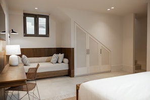 Une chambre à coucher avec un lit, un bureau avec une lampe, un canapé et une armoire.