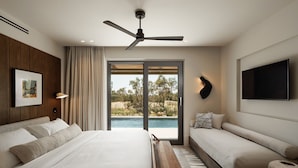 A modern bedroom with a bed, bench, TV, and a view of a pool. - Omma Suites (Naxos)