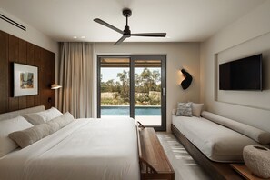 A modern bedroom with a bed, bench, TV, and a view of a pool. - Omma Suites (Naxos)