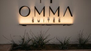 Un letrero de hotel con el nombre 'OMMA SUITES' iluminado en una pared.
