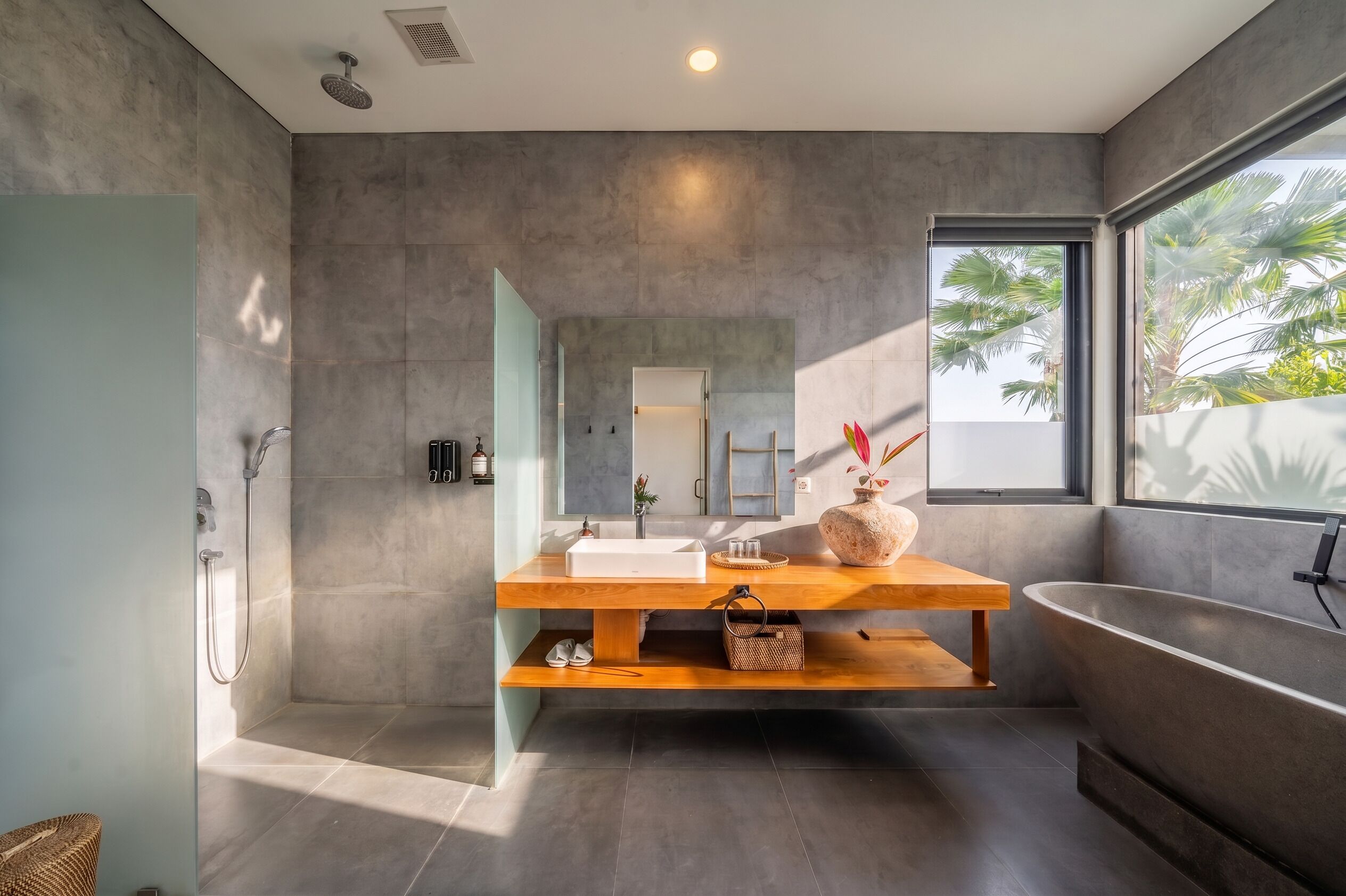 Un baño moderno con una bañera independiente, un espejo grande y un mueble de tocador de madera.