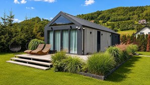 Una casa moderna con un amplio ventanal, una terraza de madera y un jardín.