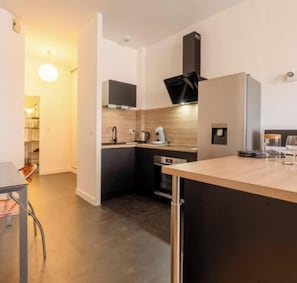 Eine moderne Küche mit dunklen Schränken, einem eingebauten Backofen und einer Kaffeemaschine.