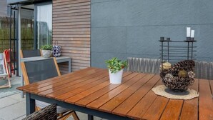Uma mesa de madeira com cadeiras, um vaso de planta e um suporte metálico decorativo com velas.